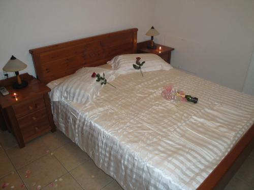 a bed with two roses on it with two night stands at Kandania Apartments in Kántanos