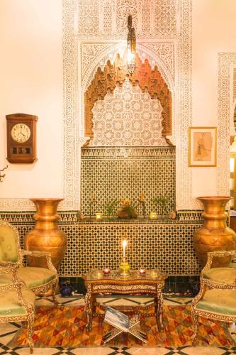 a room with a table and two chairs and a clock at Dar El Kébira in Rabat