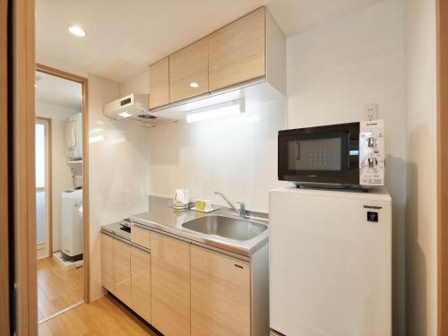 a small kitchen with a sink and a refrigerator at M´s Stay Okinawa in Chatan