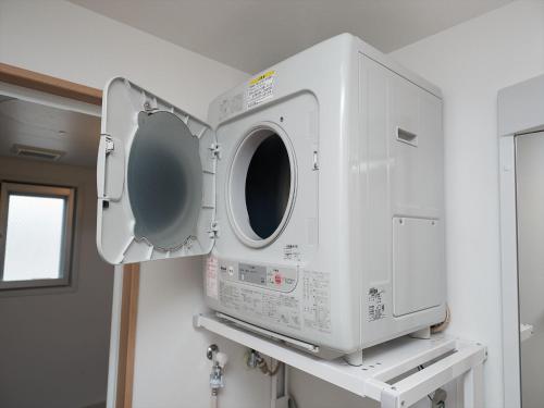 a microwave oven hanging on a wall in a bathroom at M´s Stay Okinawa in Chatan