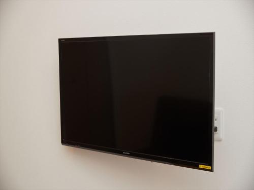a flat screen tv hanging on a wall at M´s Stay Okinawa in Chatan