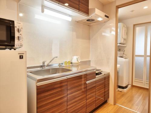 a kitchen with a sink and a refrigerator at M´s Stay Okinawa in Chatan