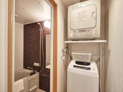 a small bathroom with a shower and a washing machine at M´s Stay Okinawa in Chatan