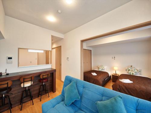a living room with a blue couch and a bedroom at M´s Stay Okinawa in Chatan