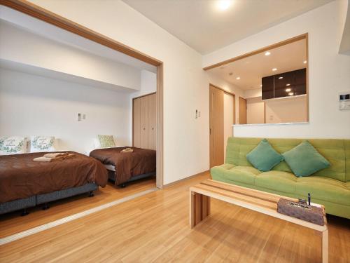 a bedroom with a bed and a green couch at M´s Stay Okinawa in Chatan