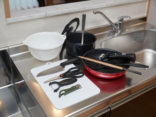 a kitchen counter with a stove with utensils on it at M´s Stay Okinawa in Chatan