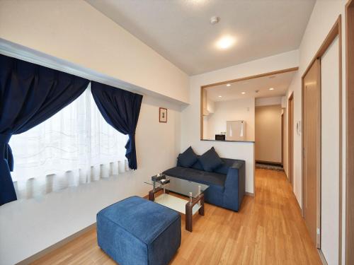 a living room with a blue couch and a window at M´s Stay Okinawa in Chatan