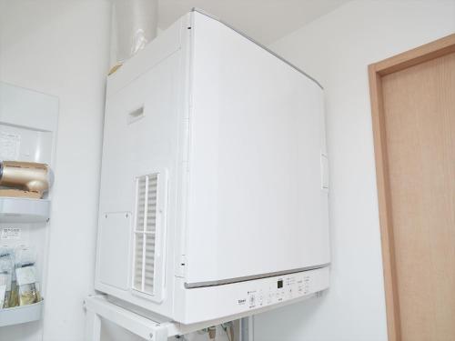 a white cabinet in a kitchen next to a refrigerator at M´s Stay Okinawa in Chatan