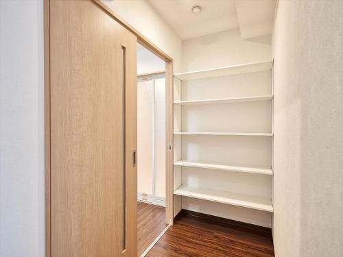 a walk in closet with white shelves and a door at M´s Stay Okinawa in Chatan