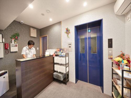 a woman standing at a counter in a kitchen at M´s Stay Okinawa in Chatan