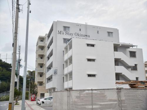 a white apartment building with a sign on it at M´s Stay Okinawa in Chatan