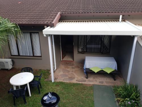 a patio with a white canopy and a table and chairs at 11 Villa Del Sol in Amanzimtoti