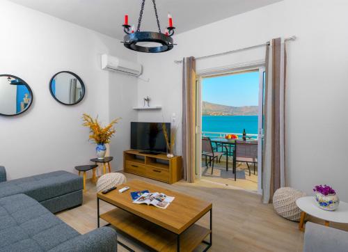 a living room with a couch and a tv and a table at Margarita's Seafront Luxury Apartment in Elounda