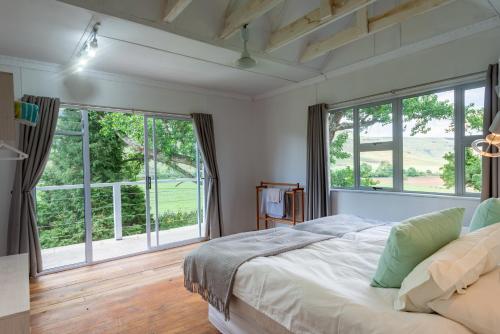 1 dormitorio con 1 cama grande y ventanas grandes en Woodcliffe Country House, en Woodcliffs