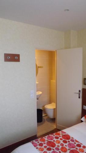 a white toilet sitting in a bathroom next to a wall at Hôtel de la Place des Alpes in Paris