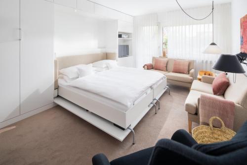 a white bedroom with a bed and a living room at Vier Häuser in Norderney