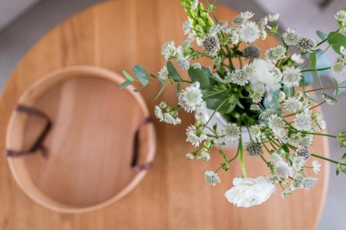 a vase of white flowers on a table with a pair of glasses at Vier Häuser in Norderney