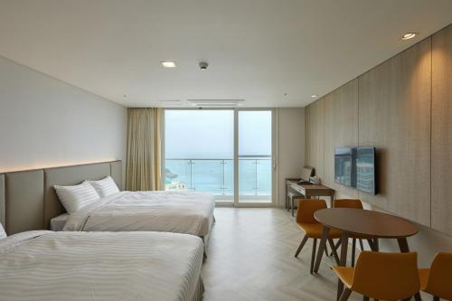 a hotel room with two beds and a table and a desk at Sol Beach Jindo in Jindo