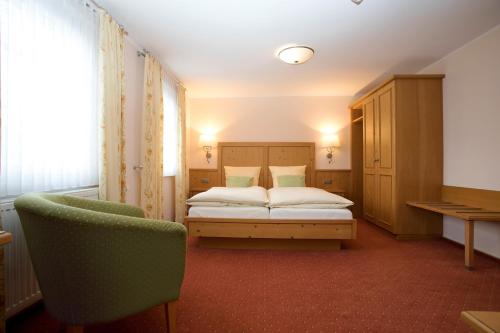 a bedroom with a bed and a chair in it at Hotel Lindenhof in Meschede