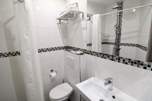 Un baño blanco con inodoro y lavabo. en Hotel des Pyrénées, en París