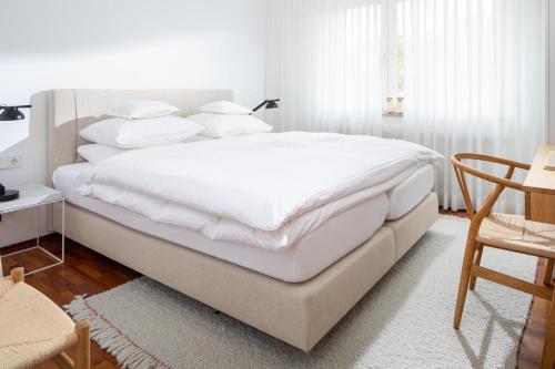 a white bedroom with a large bed with white pillows at Vier Häuser in Norderney