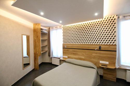 a bedroom with a bed and two windows at Hotel des Pyrénées in Paris