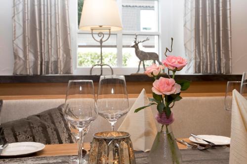 einen Tisch mit zwei Weingläsern und einem Reh im Fenster in der Unterkunft Hotel Lindenhof in Meschede