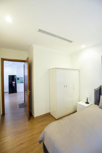 a white bedroom with a bed and a white cabinet at Full House Times City in Hanoi