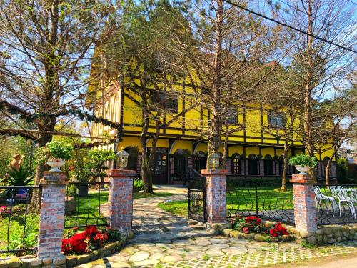 a yellow house with a black gate and flowers at Puli Story House in Puli