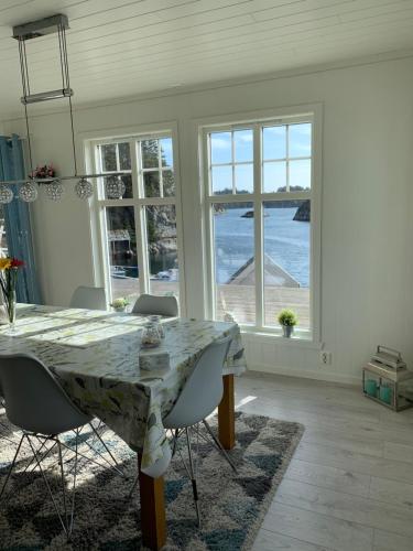 a dining room with a table and chairs and windows at Havbris in Bremnes