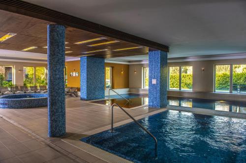 un vestíbulo con piscina y columnas en Royal Club Hotel, en Visegrád