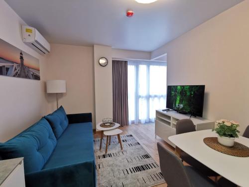 Cozy Palanga في بالانغا: غرفة معيشة مع أريكة زرقاء وتلفزيون