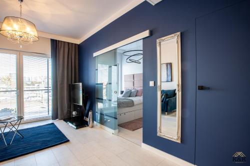 a living room with a blue wall and a mirror at K&K Apartament blisko Centrum Near City Center in Warsaw