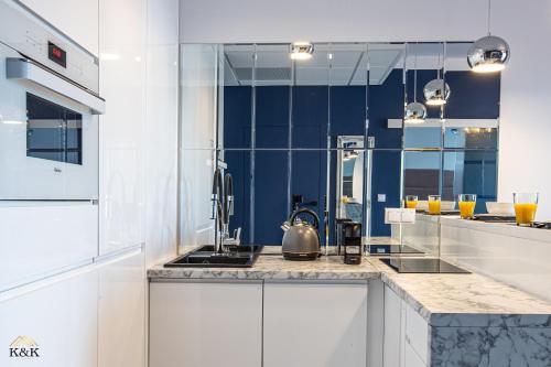 a kitchen with white cabinets and blue walls at K&K Apartament blisko Centrum Near City Center in Warsaw