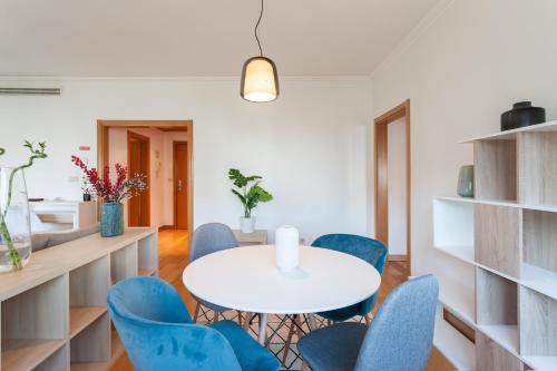 a dining room with a white table and blue chairs at Central Orient Residence - Modern, spacious and sunny! By the river! in Lisbon