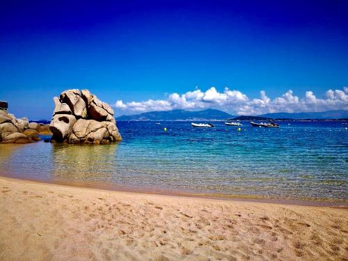 a beach with rocks in the water with boats at Senteurs du Maquis in Porticcio