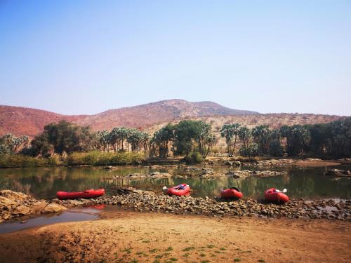 a group of kayaks on a river with mountains in the background at Omarunga Epupa-Falls Campsite in Epupa