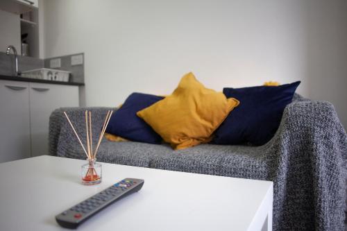 a couch with two pillows and a remote control on a table at Quirky, Stylish & Modern Studio in Central Reading in London