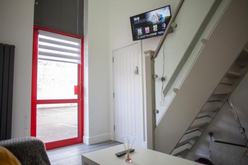 uma sala de estar com uma porta vermelha e uma escada em Quirky, Stylish & Modern Studio in Central Reading em Londres