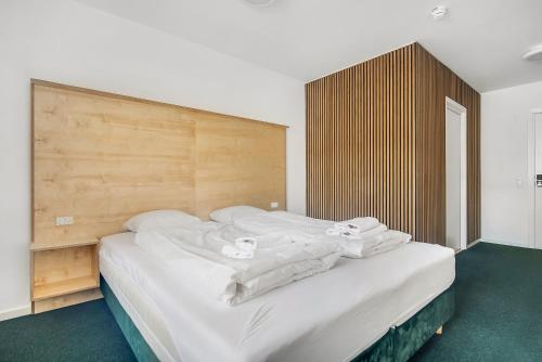 Schlafzimmer mit einem großen weißen Bett mit einem Kopfteil aus Holz in der Unterkunft Sleepcph in Kopenhagen