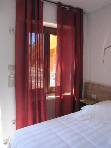 a bedroom with red curtains and a bed and a window at Vino e Turismo in San Defedente di Cervasca