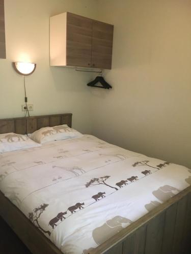 a bed with a blanket with animals on it at Geschakelde bungalow op de Veluwe "De Eekhoorn" in Otterlo