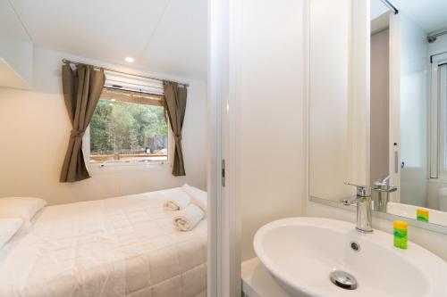 a white bathroom with a sink and a tub at Club del Sole Stella del Mare Family Collection in Castiglione della Pescaia