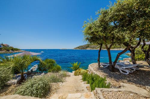 a bench sitting next to a body of water at Villa Lavanda Deluxe in Rogoznica