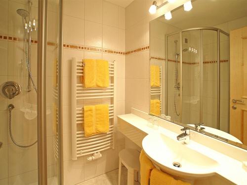 a bathroom with a sink and a shower with yellow towels at Hotel Hagerhof in Thiersee