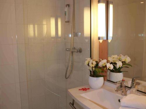 a bathroom with a shower and a sink with flowers at ibis Chateauroux in Châteauroux