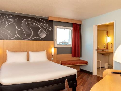 a hotel room with a bed and a window at ibis Saint-Die in Saint Die