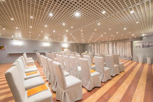 um quarto com filas de cadeiras brancas num piso de madeira em Grand Hotel Royal E Golf em Courmayeur