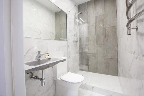 a white bathroom with a toilet and a shower at Kulikovskiy hotel in Kharkiv