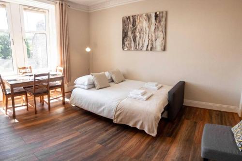 um quarto com uma cama, uma secretária e uma mesa em Bright, Spacious West-End Flat, Near University em Dundee